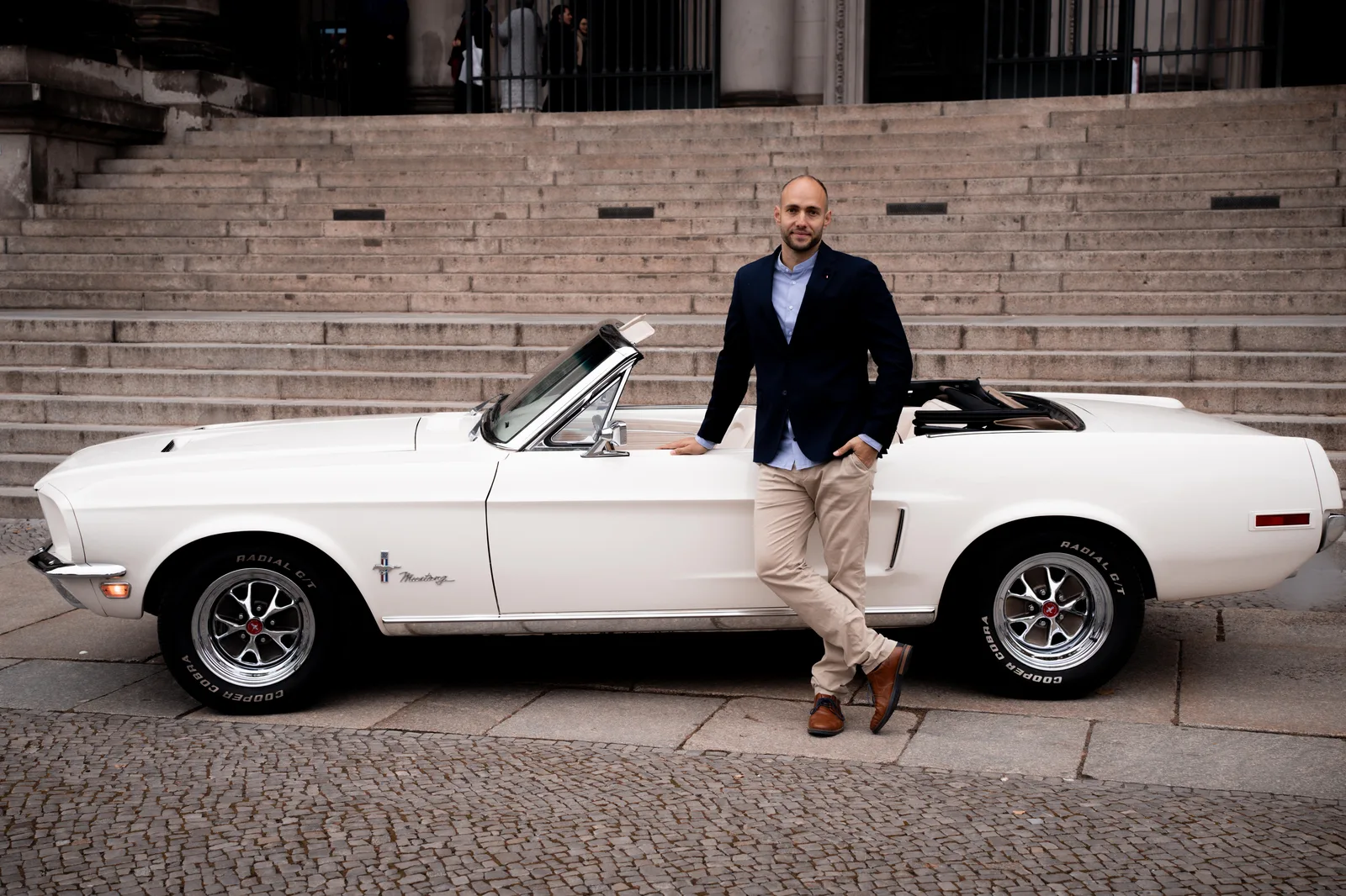 Weißer 68er Mustang mit offenem Verdeck vor einer Treppe